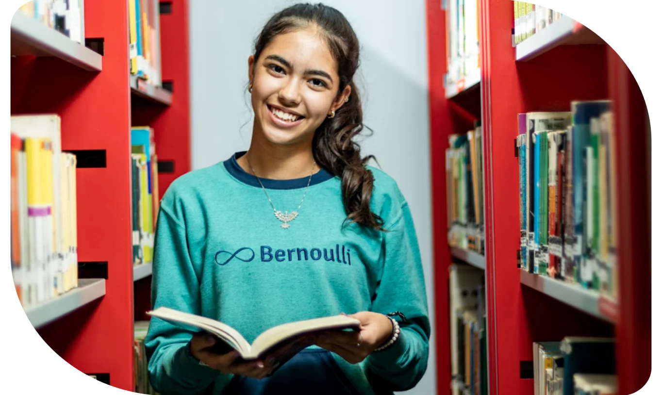 Estudante lendo um livro na biblioteca do Colégio Bernoulli.