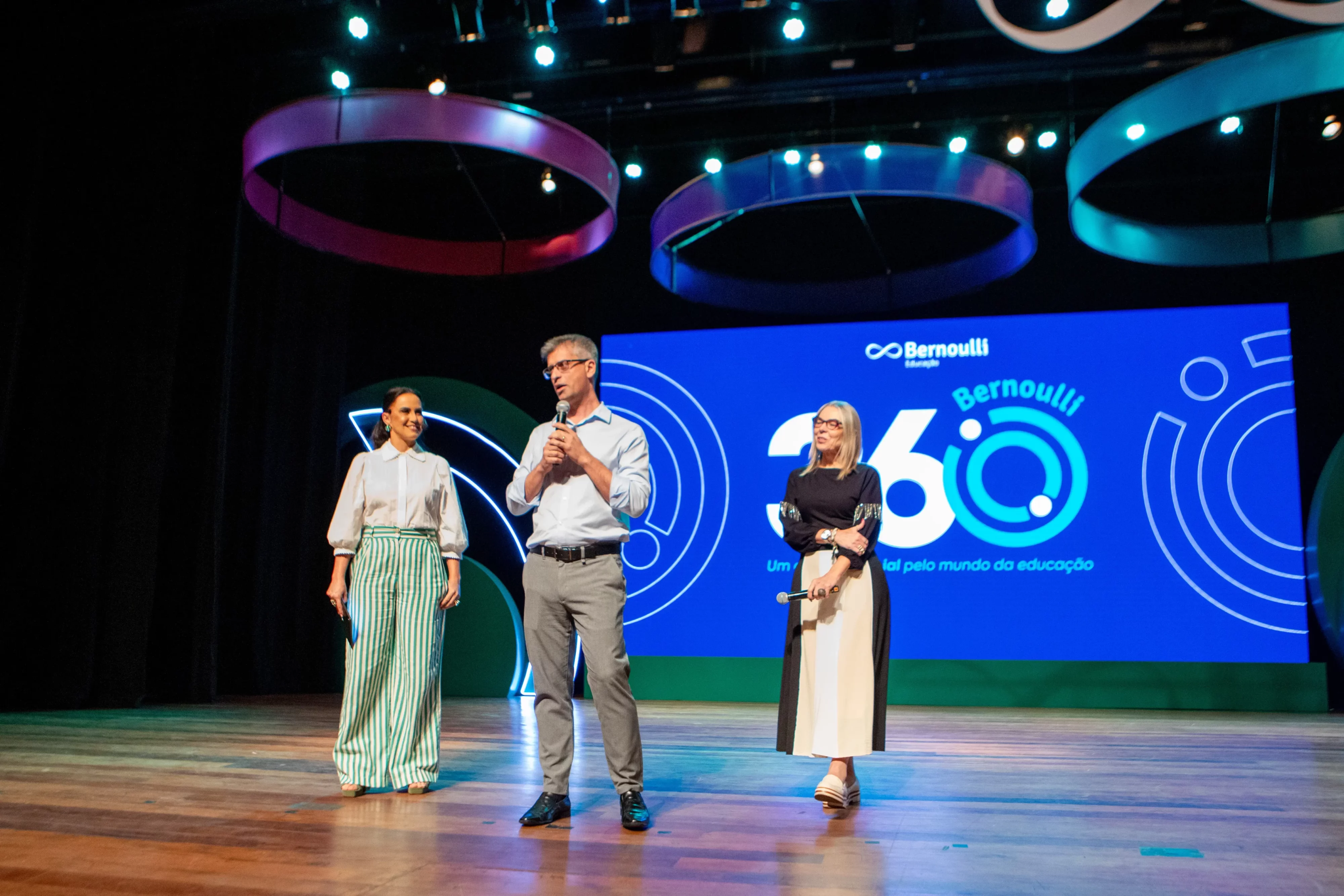 Três palestrantes no palco de um evendo do Bernoulli 360
